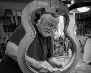 John Monteleone sanding the body of a guitar in his workshop.