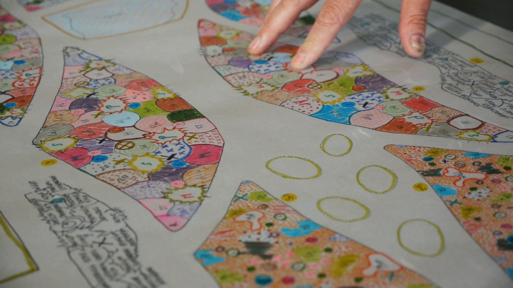 closeup of a hand over a drawing of a garden. 