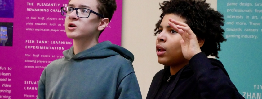 Two young boys playing a video game in the exhibition.